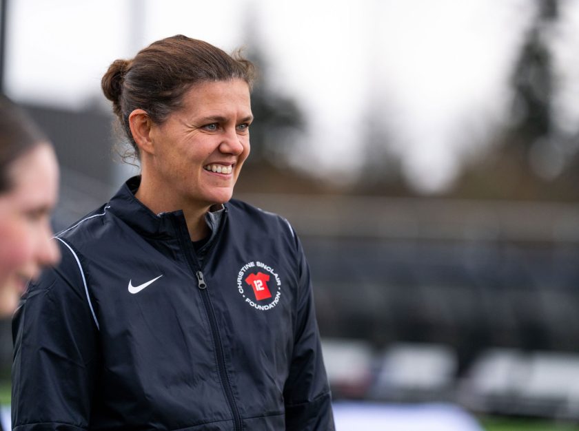 Christine Sinclair on the field, smiling as she listens to a group at the Sinclair Soccer Summit – clicking this link will open a larger version of it in the browser window.