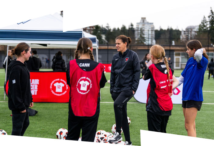 Christine Sinclair on the field, interacting with young girls wearing pinnies at the Sinclair Soccer Summit.