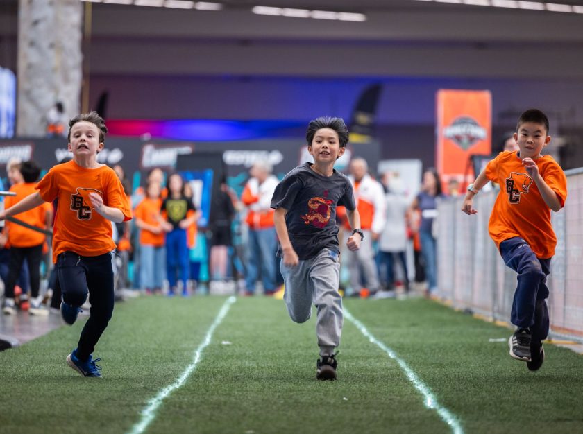 Three young boys race down a field during a kids event at the 2024 Grey Cup Festival – clicking this link will open a larger version of it in the browser window.