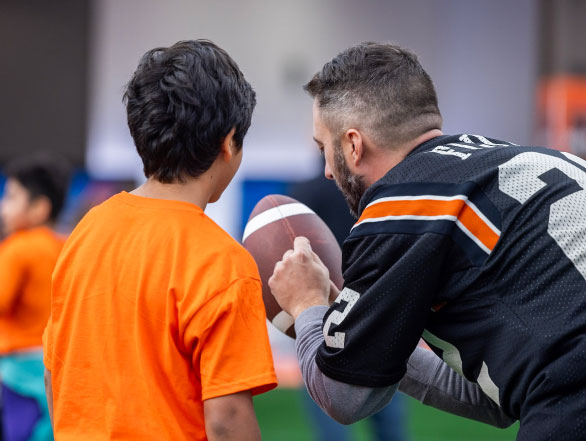 A child being taught how to kick a football.