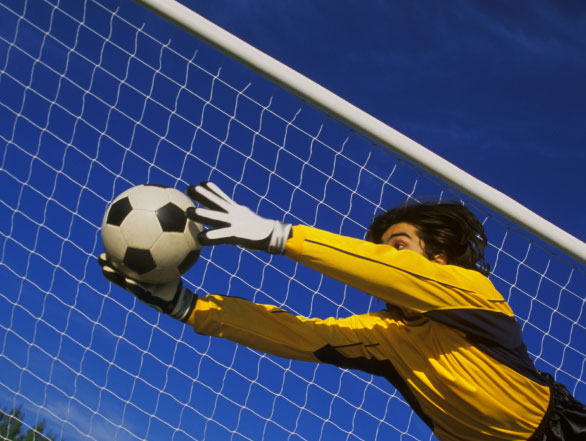 A soccer goalie jumps and reaches for a save.