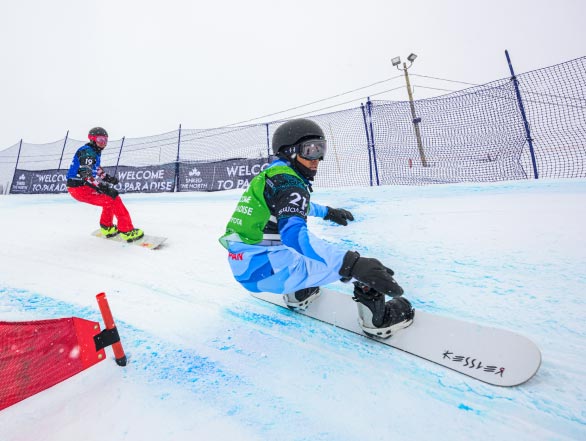 Two snowboarders carving around a slalom flag during a FIS Para Snowboard World Championship event.